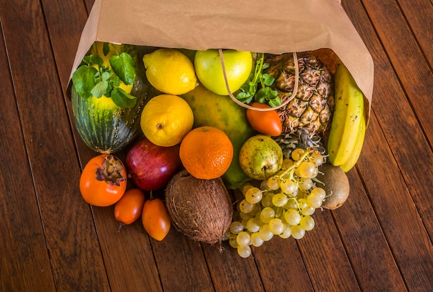 Foto een rustieke houten tafel met een papieren zak vol met veel vers geplukt vers fruit veel vitamines bij elkaar op een houten tafel