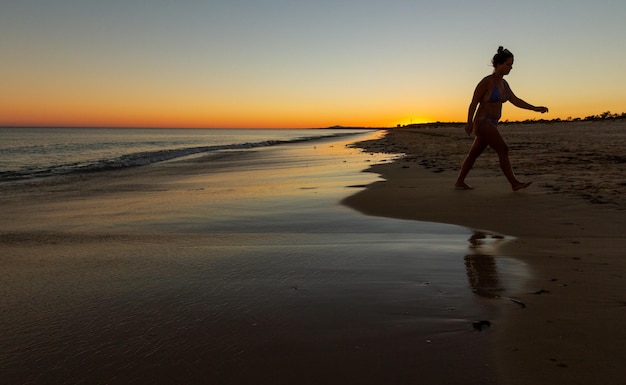 Een rustig spaans strand bij zonsondergang waar mensen lopen en rennen