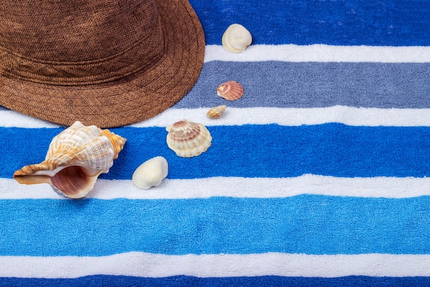 Een samenstelling van de zomervakantie op een strandhanddoek met zeeschelpen en een hoed.