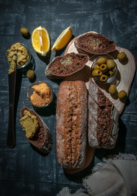 Een samenstelling van twee stokbroden van zemelen en volkoren meel Sandwich van hummus en olijven Op de houten afstand Uitzicht van bovenaf