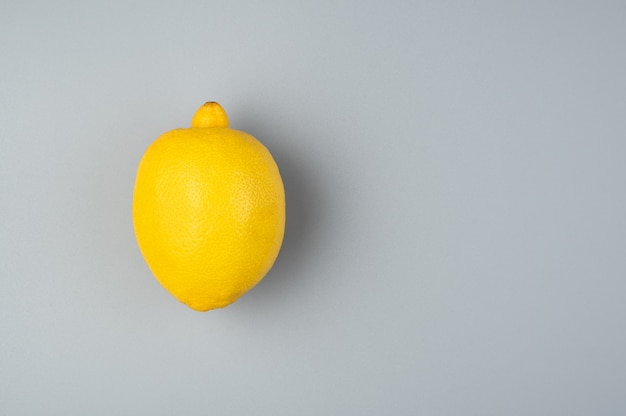 Een sappige rijpe citroen op een grijze achtergrond. Bovenaanzicht met ruimte om te kopiëren.