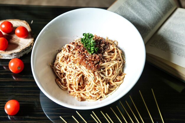Een schaal spaghetti en tomaten op tafel.