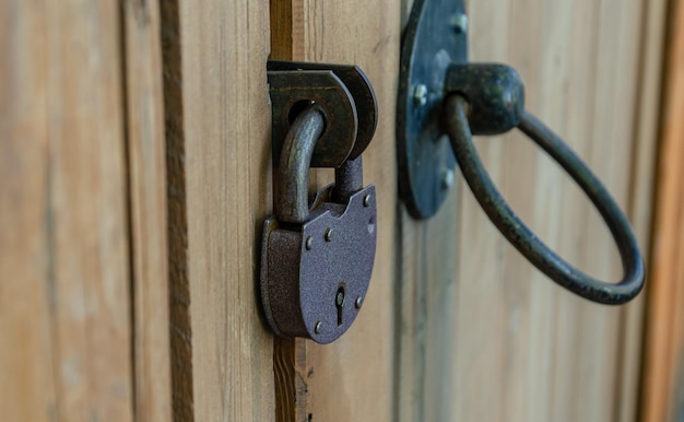 Een scharnierend ijzeren slot op een houten poort.