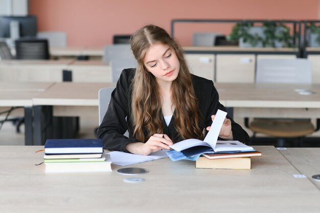 Foto een schattig 15-jarig schoolmeisje zit aan een school bureau met notitieboeken en boeken en studies