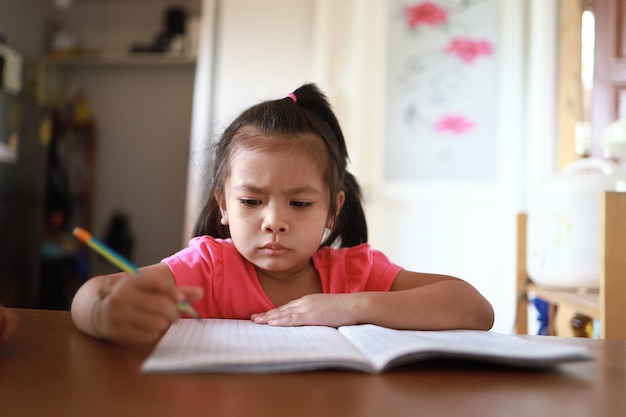 Een schattig aziatisch meisje dat overdag thuis huiswerk maakt her