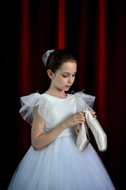 Een schattig ballerinameisje in een witte jurk op een rode achtergrond Art Dance Beauty