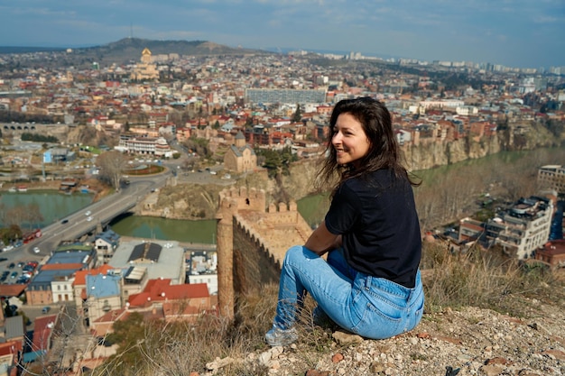 Een schattig brunette meisje geniet van het prachtige landschap van Tbilisi vanaf de heuvel De hele stad aan haar voeten