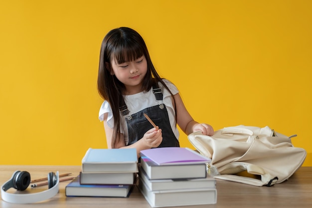 Een schattig jong Aziatisch meisje bereidt haar briefpapier voor of pakt haar schooltas in voor haar schooldag