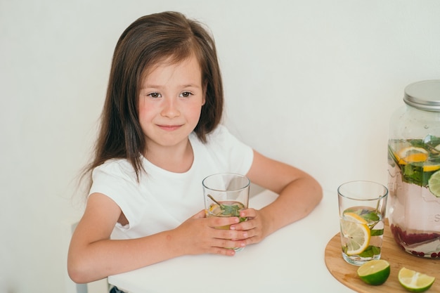 Een schattig kind drinkt zelfgemaakte limonade gezonde limonade met citroen en limoen zomerverkoelend drankje voor ch...