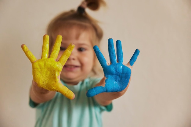 Een schattig kind schilderde zijn handen in de kleuren van de Oekraïense vlag