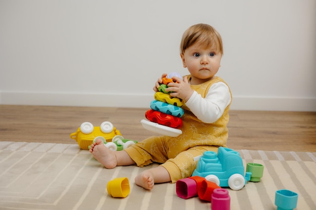 Een schattig kind speelt met een kleurrijke regenboogspeelgoedpiramide Speelgoed voor kleine kinderen