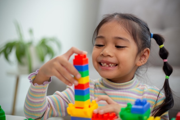 Een schattig klein meisje dat speelgoedblokken speelt in een heldere kamer.