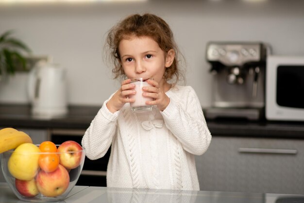 Een schattig klein meisje drinkt yoghurt Het concept van gezond eten Zorgen voor de gezondheid van het kind