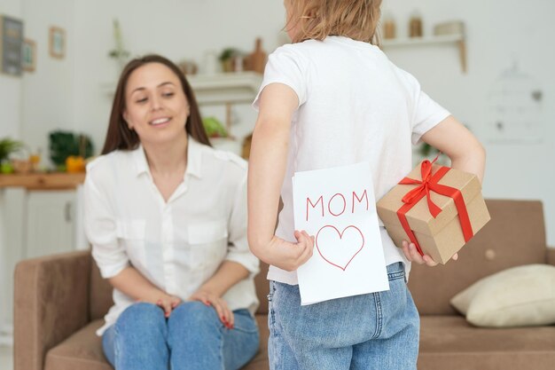 Een schattig klein meisje geeft een handgemaakte kaart met een hartje aan haar moeder