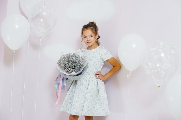 Een schattig klein meisje glimlacht en poseert met een boeket bloemen