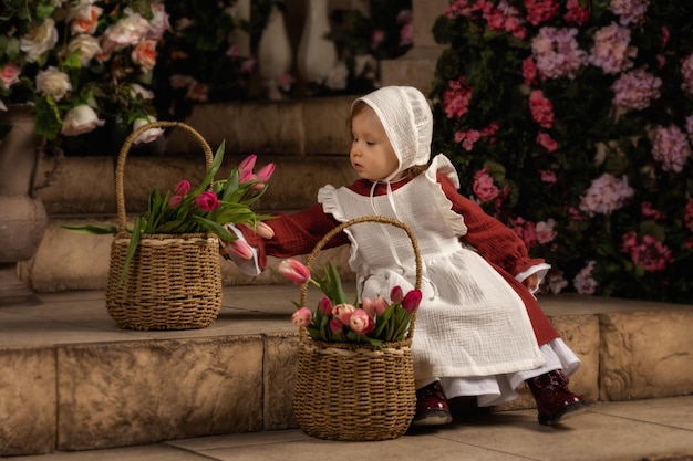 Een schattig klein meisje in een mooie jurk verzamelt boeketten tulpen in manden