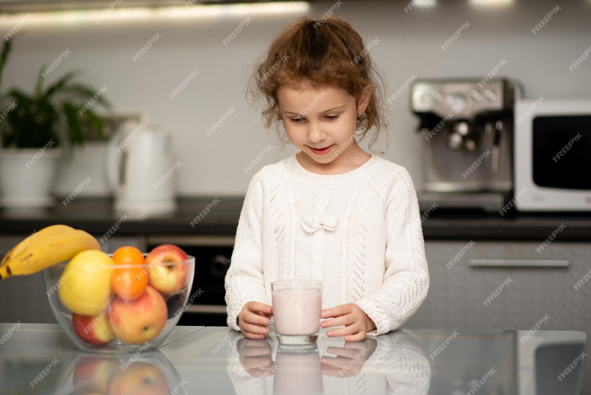 Een klein meisje in witte trui drinkt yoghurt jeugd zorgen voor de gezondheid van het | Foto