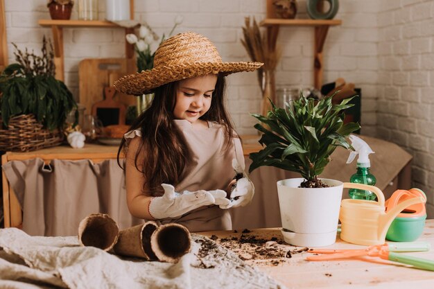 Een schattig klein meisje plant en geeft thuis een bloem in een pot water Een kleine zomerbewoner zorgt voor thuisbloemen Earth Day