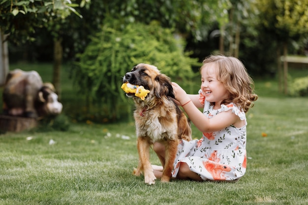 Een schattig klein meisje speelt met haar hond buiten op gras thuis