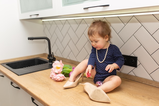 Een schattig klein meisje zit in de keuken met een boeket roze tulpen mooie cadeau ansichtkaart