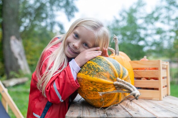 Een schattig meisje dat bij de tafel staat met pompoenen aan