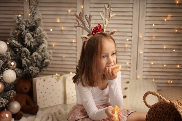 een schattig meisje in een nieuwjaarskostuum eet een sinaasappel