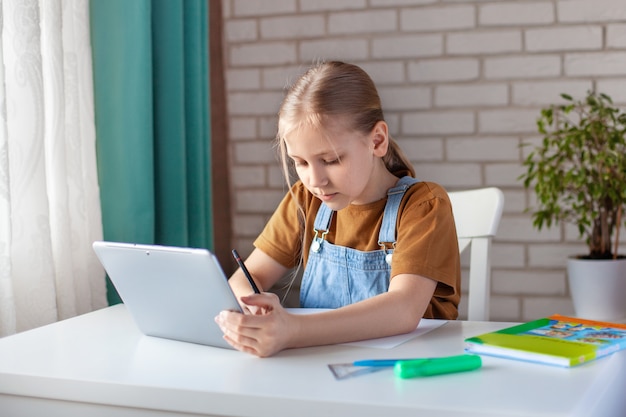 Een schattig meisje maakt haar huiswerk met behulp van een tablet