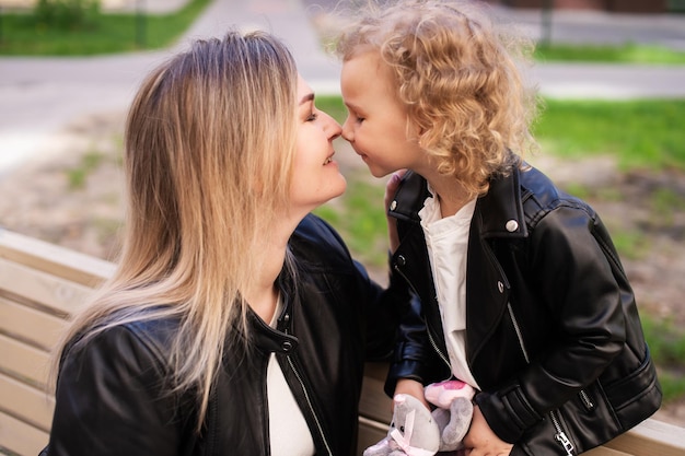 Een schattig meisje zit met haar moeder te lachen en raakt haar aan met haar neus