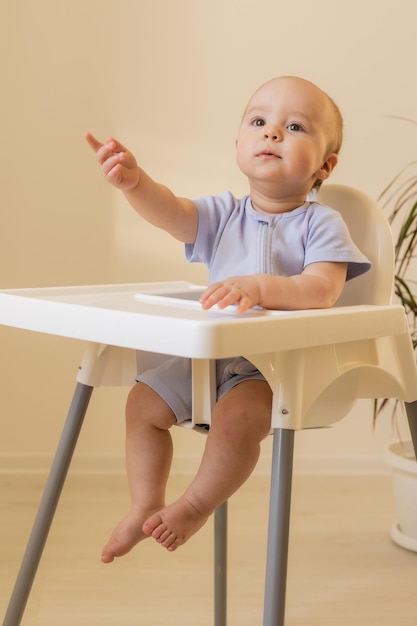 Een schattige baby zit thuis in een kinderstoel in de ruimte voor babyvoeding in de keuken voor tekst van hoge kwaliteit