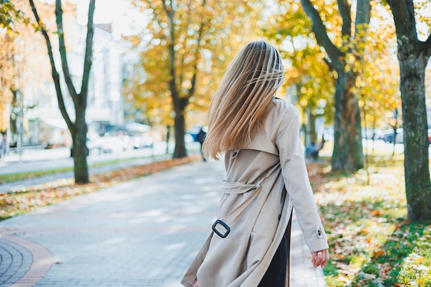 Een schattige blonde jonge vrouw rent in het herfstpark