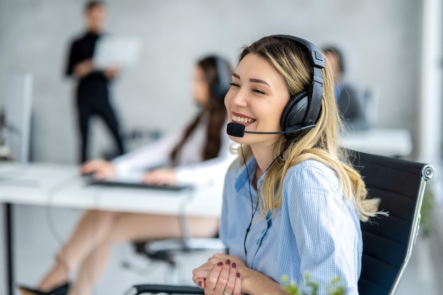 Een schattige blonde vrouw met een headset die praat met een klant in een callcenter.