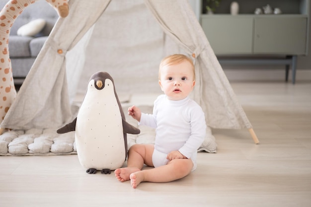 Een schattige gezonde babyjongen in een ruime lichte kinderkamer thuis met een wigwam zacht speelgoed kindertextiel Een kind speelt in de woonkamer van het huis