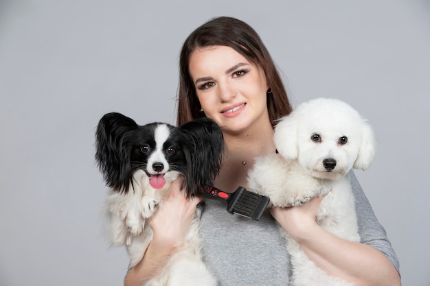 Een schattige jonge vrouw houdt haar papillon en bichon puppy vast