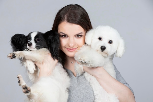 Een schattige jonge vrouw houdt haar papillon en bichon puppy vast