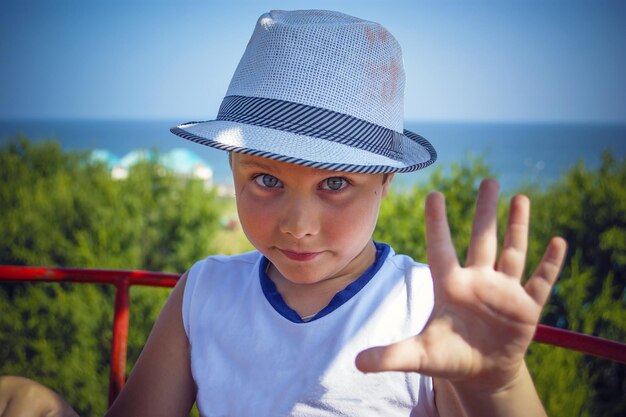 Een schattige jongen met een hoed stak zijn hand op ter begroeting.