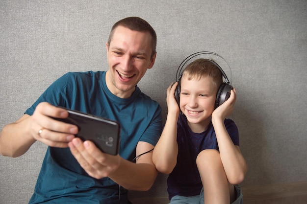 Een schattige jongen met een koptelefoon zit naast zijn vader Videobellen