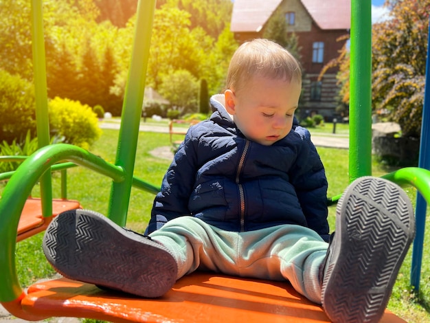 Een schattige jongen van anderhalf jaar rijdt op een schommel achtertuin van het huis kinderanimatie selectieve aandacht