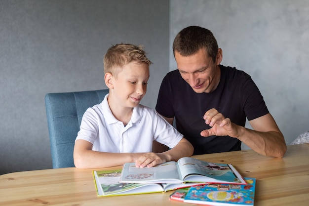 Een schattige jongen zit met zijn vader aan tafel en kijkt naar een boek over slangen