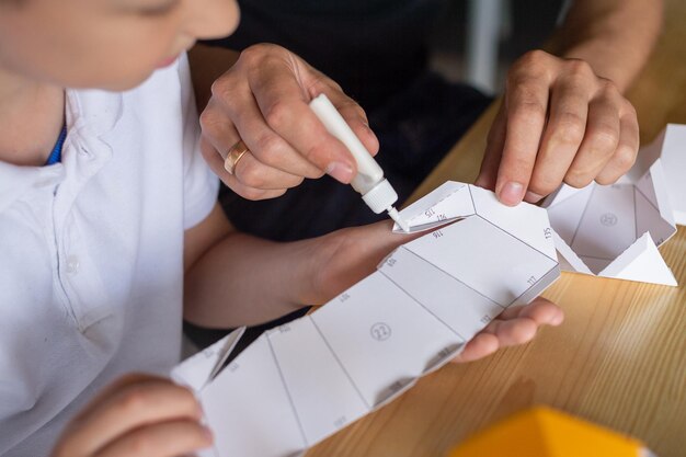 Een schattige jongen zit met zijn vader aan tafel en verzamelt origami