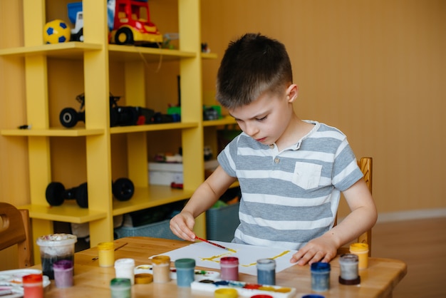 Een schattige kleine jongen speelt en schildert in zijn kamer. recreatie en amusement. blijf thuis.