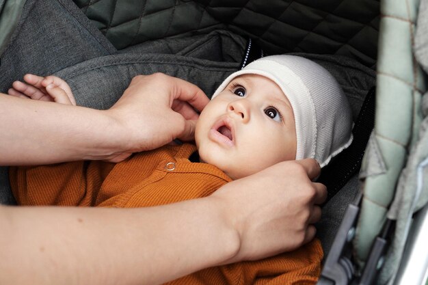 Een schattige kleine jongen zit in een kinderwagen buiten in een park op een warme, zonnige dag Portret van een kind in een kinderwagen