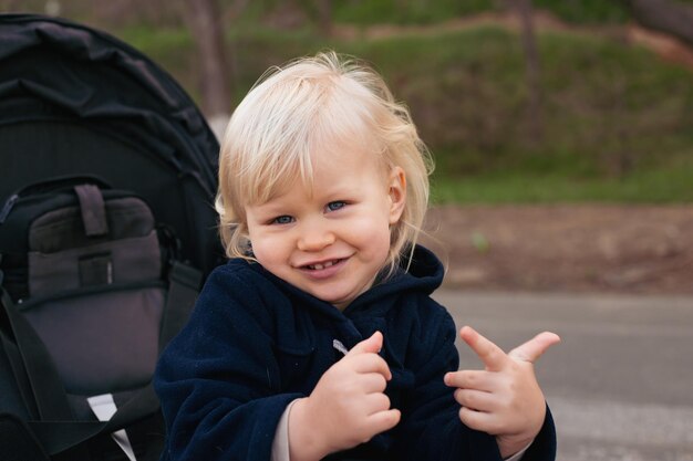 Een schattige kleine mooie jongen zit en lacht in een kinderwagen