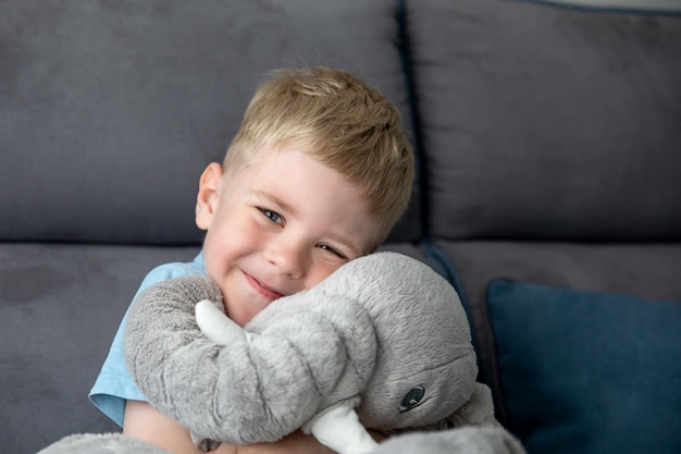 Een schattige lachende kleine jongen knuffelt een knuffel, hij is blij. Het concept van de kindertijd.