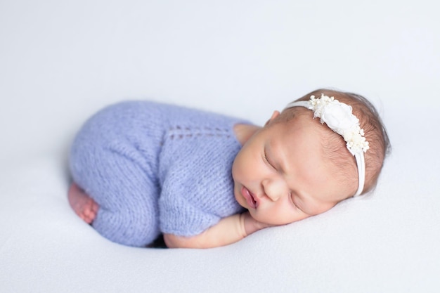 Een schattige pasgeboren baby in een gebreid pak op een witte achtergrond ligt op haar buik te slapen Kindertijd