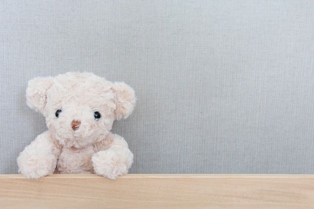 Een schattige teddybeer vangt op een houten bord op grijs