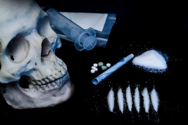 Een schedel en een injectiespuit liggen op een tafel met pillen en pillen.