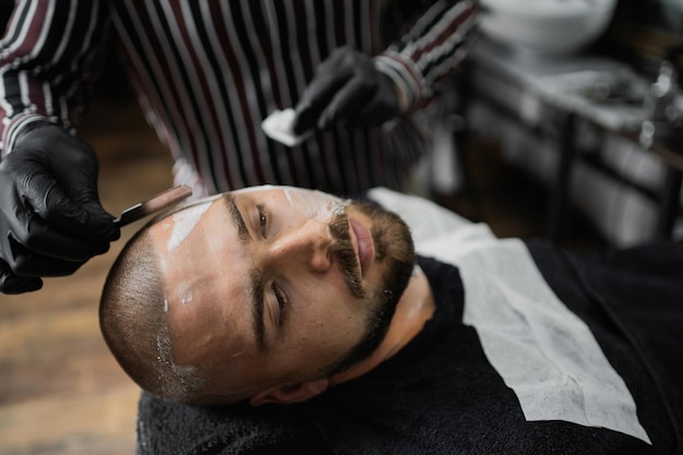 Een scheermesmeester scheert zijn baard naar de klant Schoon haar donkerharig jong