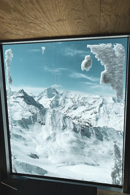 Een schilderachtig uitzicht op besneeuwde bergen door een glazen raam