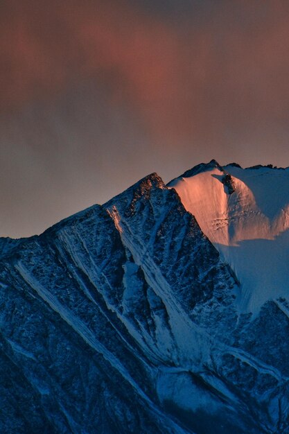 Een schilderachtig uitzicht op besneeuwde bergen tegen de hemel bij zonsondergang