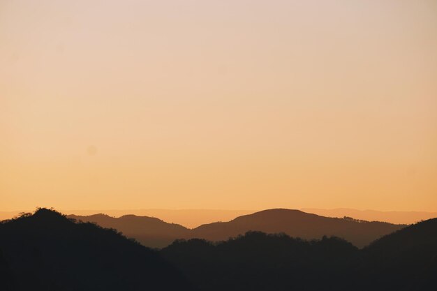 Foto een schilderachtig uitzicht op silhouette bergen tegen een oranje hemel